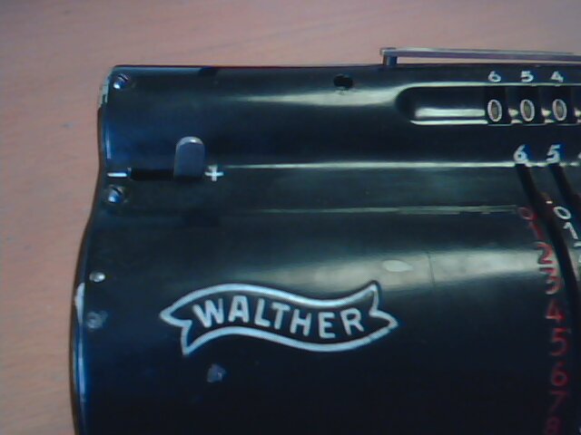 Nad logem firmy je páčka která udává, zda počítadlo otáček pracuje souhlasně nebo nesouhlasně s otáčením hlavní kliky.